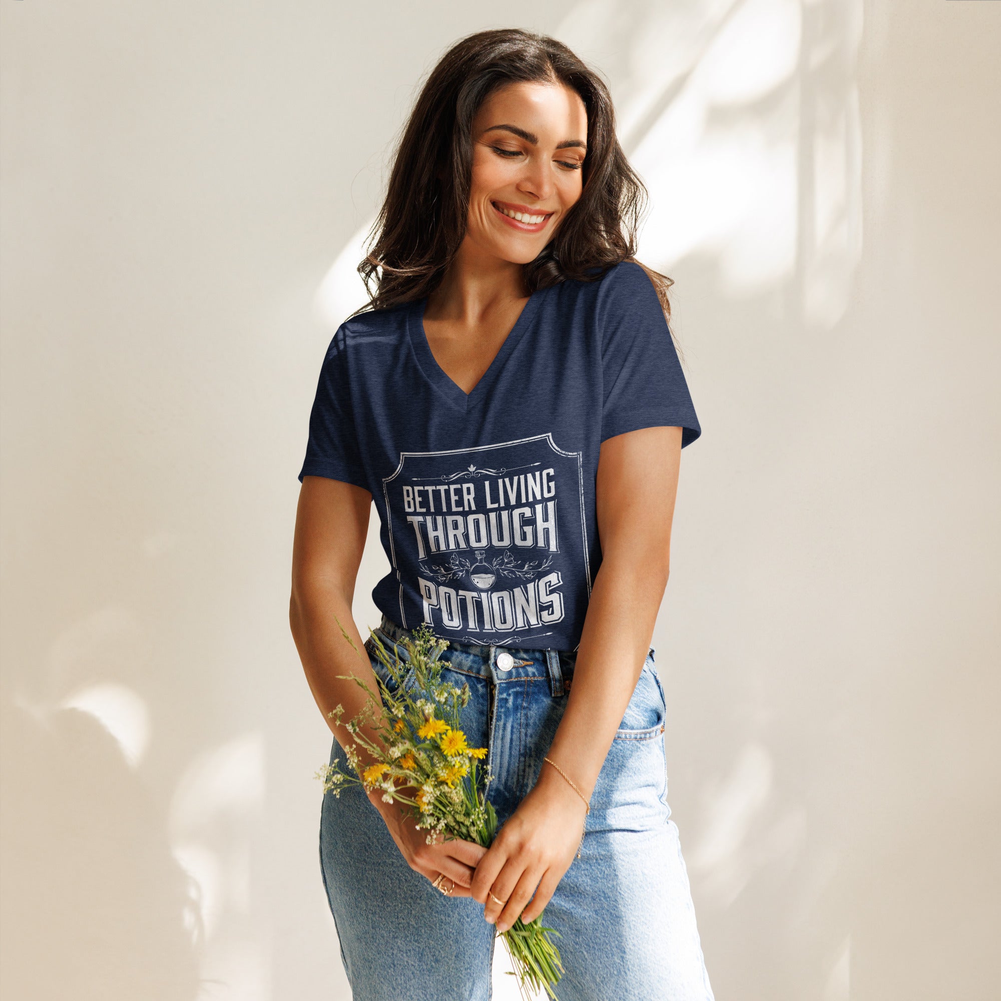 Woman wearing a blue t-shirt with our better living through potions design, holding flowers against a neutral background