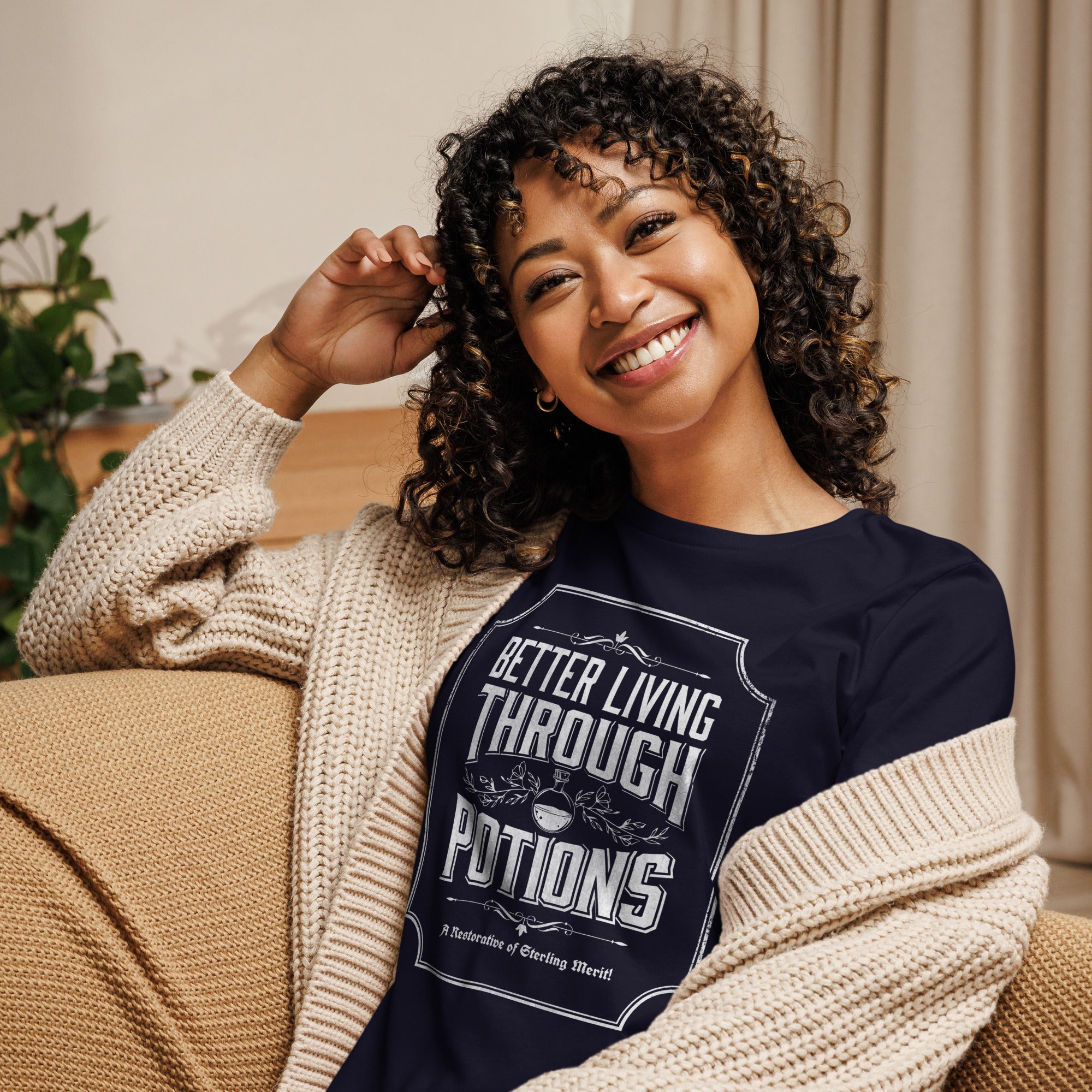 Model wearing women's better living through potions t-shirt sitting on couch