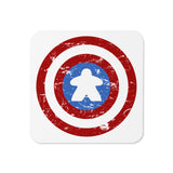 A coaster with a cork backing printed with a red, white, and blue shield design featuring a meeple at its center in place of a star.