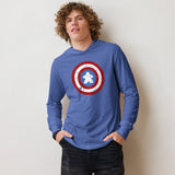 A young man with curly brown hair wearing a blue long-sleeve hooded shirt with a captain meeple shield on the chest, paired with black denim shorts, standing against a plain off-white wall.