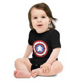 An infant onesie with snap closures printed with a red, white, and blue shield design featuring a meeple at its center in place of a star.