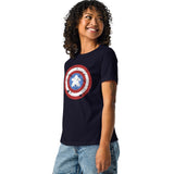 A woman modeling a navy blue t-shirt with a distressed Captain shield graphic on the chest with a meeple at the center, paired with denim shorts, against a plain white background.