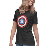 A woman wearing a dark heather gray t-shirt with a distressed Captain shield graphic on the front with a meeple at the center, paired with blue jeans, against a plain white background.