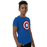 A young boy wearing a royal blue t-shirt with a Captain Meeple shield graphic on the chest, paired with black pants, standing against a plain white background.
