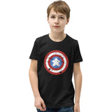 A young boy wearing a black crewneck t-shirt with a distressed Captain Meeple shield graphic on the chest, paired with blue jeans, set against a plain white background.