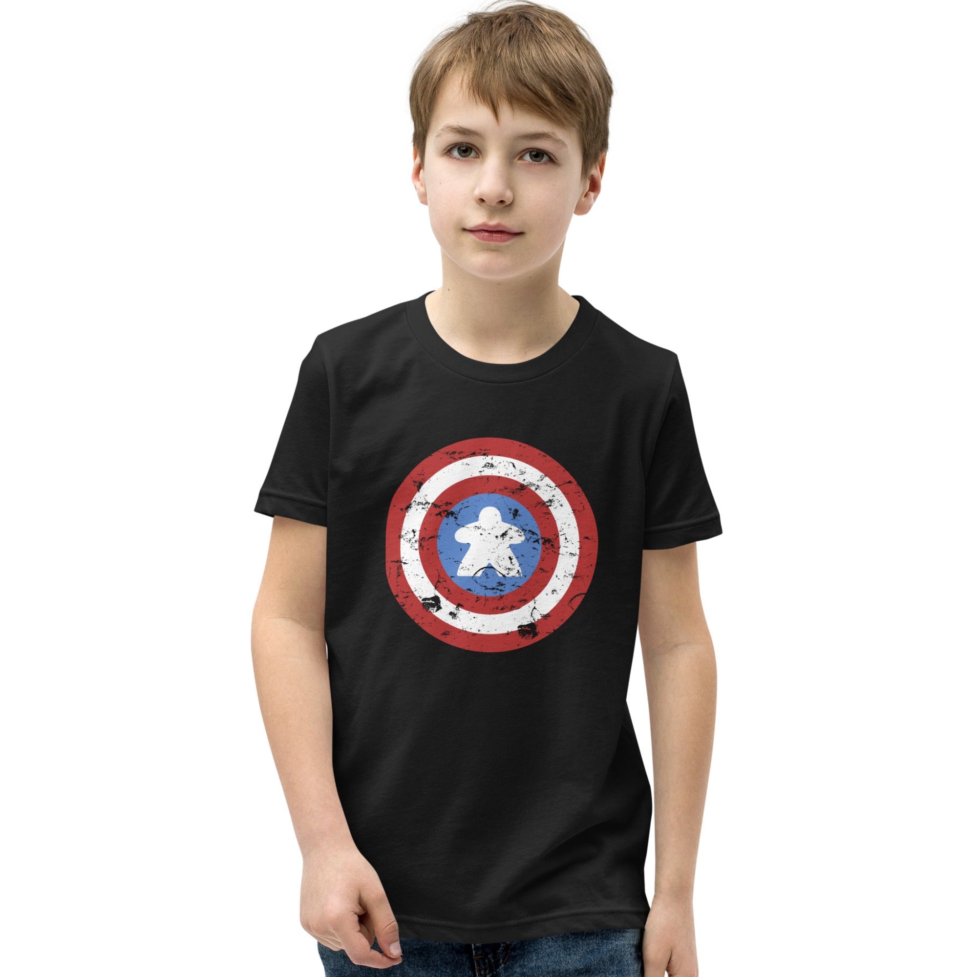 A young boy wearing a black crewneck t-shirt with a distressed Captain Meeple shield graphic on the chest, paired with blue jeans, set against a plain white background.