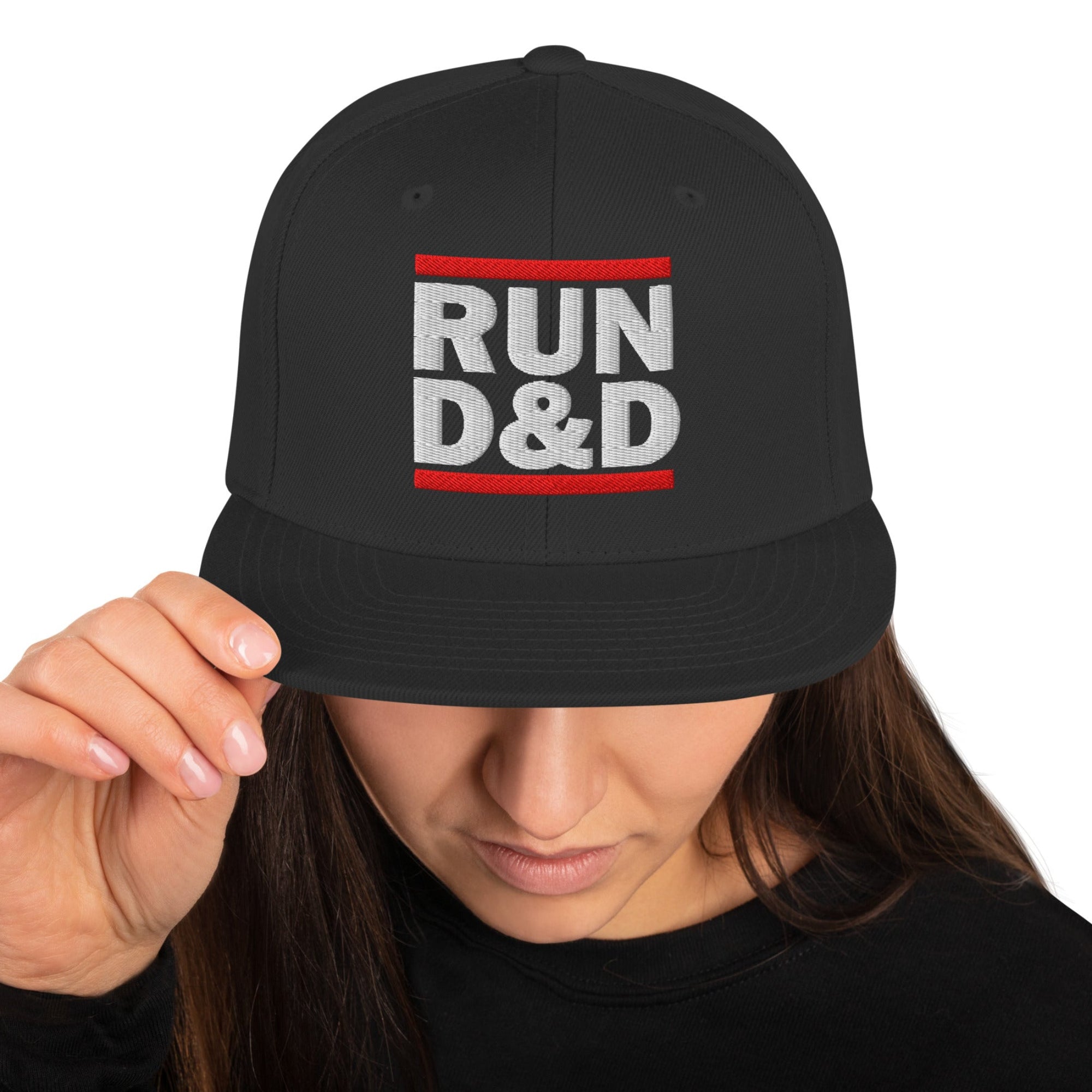 Woman with head down wearing a black snapback flat bill hat with the Run D&D Logo on the front