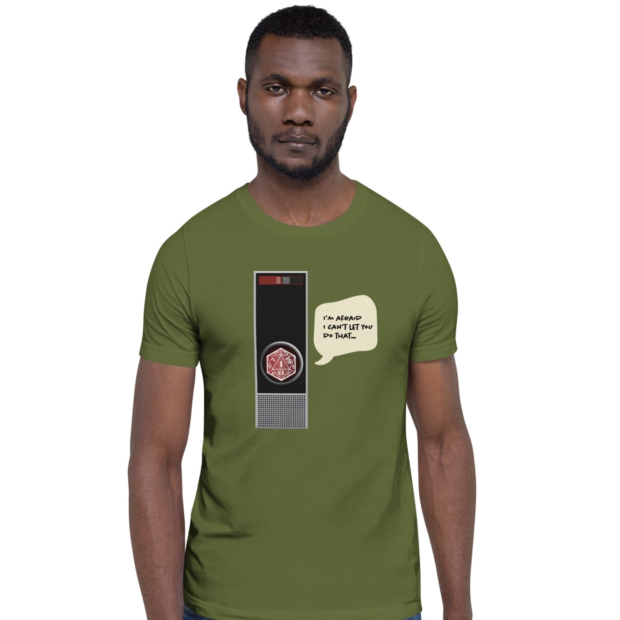 A man wearing an olive green t-shirt with a retro computer graphic and speech bubble on the front, paired with blue jeans, against a plain white background.